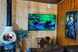 a living room with a wood wall with a fireplace at Chalé de montaña con Jacuzzi in Guarne