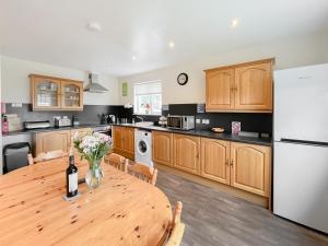 a kitchen with a wooden table and a white refrigerator at Uk47550 - Cairnsmore Cottage in Newton Stewart