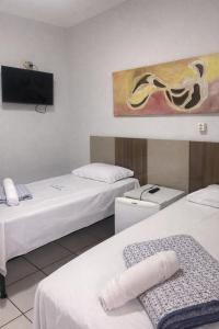 a room with two beds and a flat screen tv at Hotel Shx Goiânia in Goiânia
