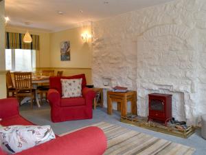 a living room with a stone fireplace and red chairs at The Anchorage in Staithes