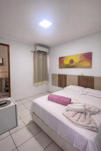 a bedroom with a large white bed and a painting on the wall at Hotel Shx Goiânia in Goiânia