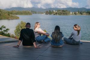 a group of people sitting on a dock by the water at Bliss Sanctuary Vista - Glamping and Club in Guatapé