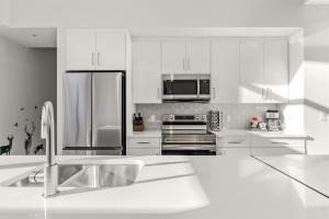 a kitchen with white cabinets and a stainless steel refrigerator at Cloudline Vista 3 BdrmTownhouse w Private Garage Views Pool Walk Downtown in Canmore