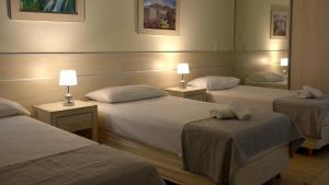 a hotel room with three beds and a mirror at LS Hotel in Salta