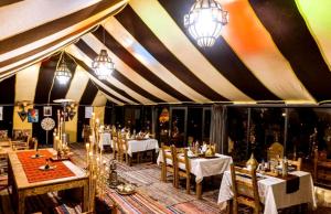 a dining room with tables and chairs in a tent at Starry Nights Camp in Merzouga
