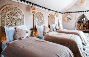 a bedroom with three beds in a room at Starry Nights Camp in Merzouga