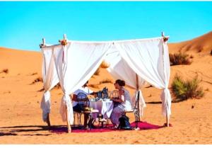 a man sitting at a table in the desert at Starry Nights Camp in Merzouga