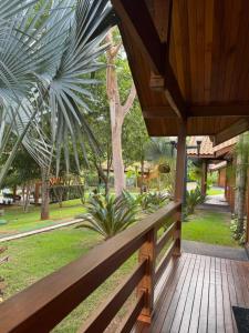 a wooden porch with a wooden fence and palm trees at Chalé dos Lagos Ecoresort in Mandaguaçu +10 photos