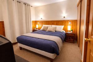 a bedroom with a large bed with blue sheets and pillows at Refugio del volcán in Pucón +49 photos