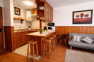 a kitchen with wooden cabinets and a kitchen island with bar stools at Refugio del volcán in Pucón