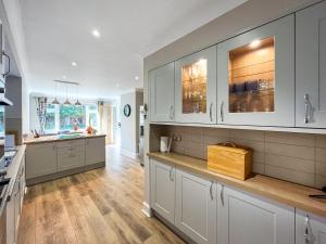 a kitchen with white cabinets and a wooden floor at Casa Rosa in Prestatyn +6 photos