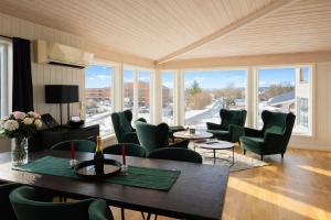 a room with green chairs and tables and windows at KB - Villa sentrum Leknes in Vestvågøya