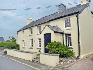 a white house with a blue door on a street at Ty Cornel in Aberporth