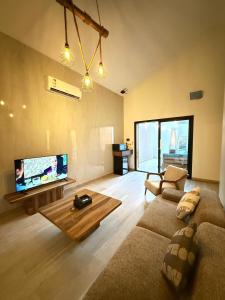a living room with a couch and a flat screen tv at اكواخ سنتارا الريفيه in Taif