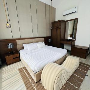 a bedroom with a large white bed and a chair at اكواخ سنتارا الريفيه in Taif