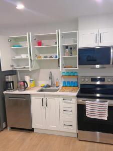 a kitchen with white cabinets and a sink and a stove at Kris Anclam in Langley +12 photos