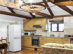 a kitchen with wooden cabinets and a white refrigerator at The Hayloft - Uk50027 in Liskeard