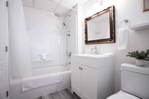 a white bathroom with a sink and a mirror at Pet Friendly Licensed Suite on Haskap Farm in Kelowna