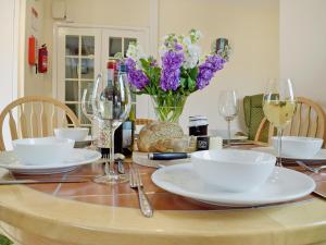 a table with plates and wine glasses and purple flowers at Ty Cornel in Aberporth +8 photos