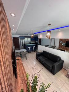 a living room with a black couch and a kitchen at Elegance Residences Cumbuco in Cumbuco
