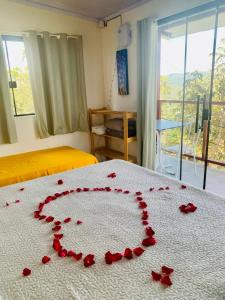 a bed with red rose petals on it at Chales Estrela Veadeiros Com Ofurô in Alto Paraíso de Goiás +26 photos