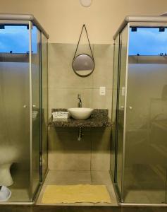 a bathroom with a sink and a glass shower at Chales Estrela Veadeiros Com Ofurô in Alto Paraíso de Goiás