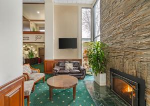 a lobby with a fireplace and couches and a tv at Rogue Regency Inn Medford Airport in Medford