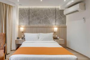 a bedroom with a large bed with an orange blanket at City Garden Hotel Makati in Manila