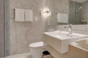 a white bathroom with a sink and a toilet at City Garden Hotel Makati in Manila