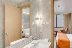a bathroom with a sink and a mirror and a bed at City Garden Hotel Makati in Manila +136 photos