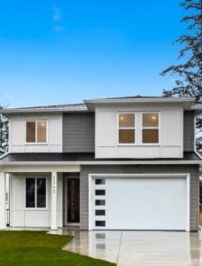 a white house with two white garage doors at Quiet Private Room Victoria - PS5, Fast WiFi, Parking in Langford