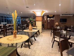 a dining room with tables and chairs and flowers on tables at Gran Lençóis Flat Residence Mandacaru 411 in Barreirinhas