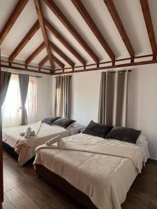 two beds in a room with wooden ceilings and windows at Casa Silvestre in Villa de Leyva