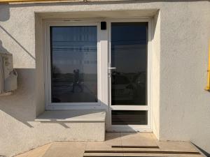 a white door with a window on the side of a building at Best4You Apartment Therme Airport in Baloteşti