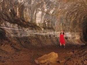 a woman in a red dress standing in a cave at Pescadito in Puerto Ayora