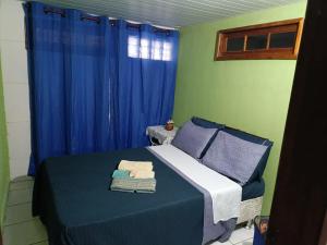 a bedroom with a bed with blue sheets and blue curtains at Jully''s house in Arraial do Cabo