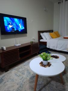 a living room with a bed and a tv on the wall at BlueByMis in Muchatha