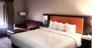 a hotel room with a large bed and a chair at Baymont by Wyndham Midland TX in Midland