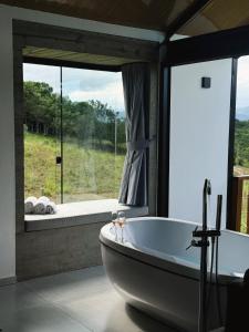 a bath tub in a bathroom with a large window at Hospedagem na natureza in Garopaba