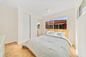 a white bedroom with a large bed and a window at Modern Family Home Near Fiona Stanley & Murdoch Uni in Perth