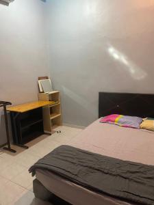 a bedroom with a bed and a desk with a laptop at Best Homestay in Kuala Rompin