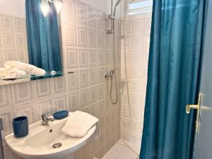 a bathroom with a sink and a shower with a blue shower curtain at Sweet Nest Villa in Sainte-Rose
