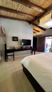 a bedroom with a bed and a desk with a television at Hostería Terrazas de la Posta in Purmamarca
