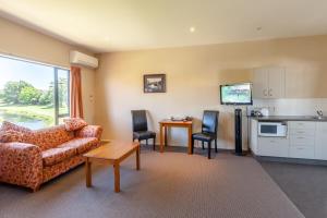 a living room with a couch and a table and a kitchen at Waterfront motel in Blenheim +15 photos