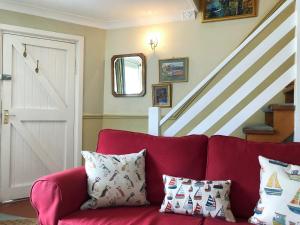 a red couch with pillows in a room with stairs at The Anchorage in Staithes