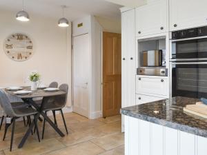 a kitchen with white cabinets and a table with chairs at Bank Lane House in Freckleton +21 photos