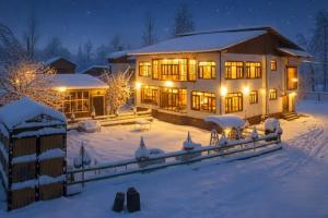 a house covered in snow at night with lights at Gulmarg Gul Sitara Resorts in Gulmarg
