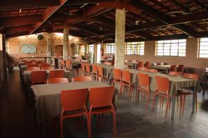 a dining room with tables and orange chairs at Pousada Corujas in Cajuru do Sul