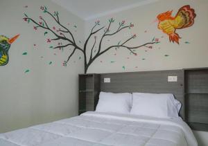 a bedroom with a bed with a tree and birds on the wall at Mariandes Hostel in Huaraz