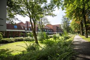 レーアにあるHotel Ostfriesen Hofの木々や建物が並ぶ庭園内の通路